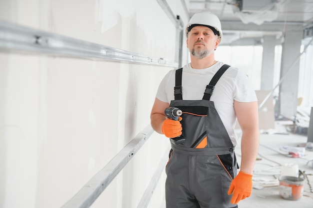 Hombre trabajador de paneles de yeso instalando láminas de yeso en la pared