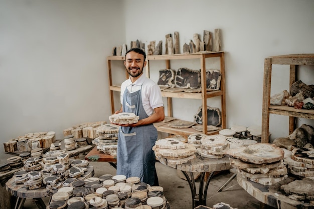 Hombre trabajador de la tienda de artesanía de piedra sonriente que sostiene artesanías de piedra cortada en el almacén