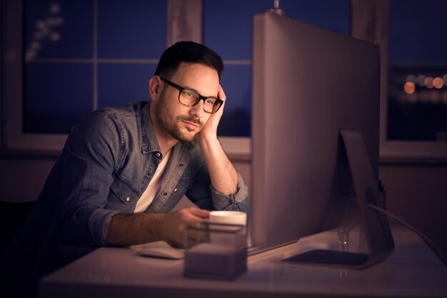 Hombre trabajando en la computadora en casa por la noche