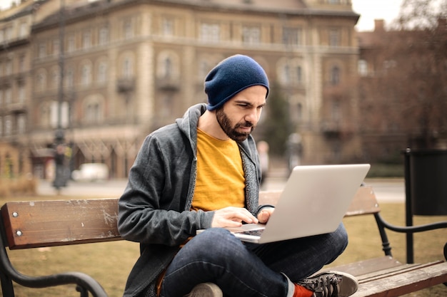 Hombre trabajando en una computadora portátil en un banco