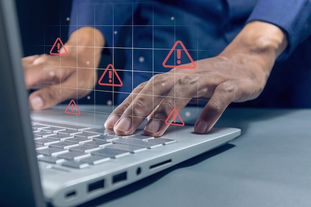 Hombre trabajando en una computadora portátil con un triángulo rojo señal de advertencia de precaución en la pantalla para el error de notificación