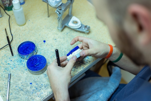 Hombre trabajando en dientes falsos en su taller