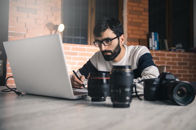 Foto hombre trabajando en equipo con lente en el escritorio