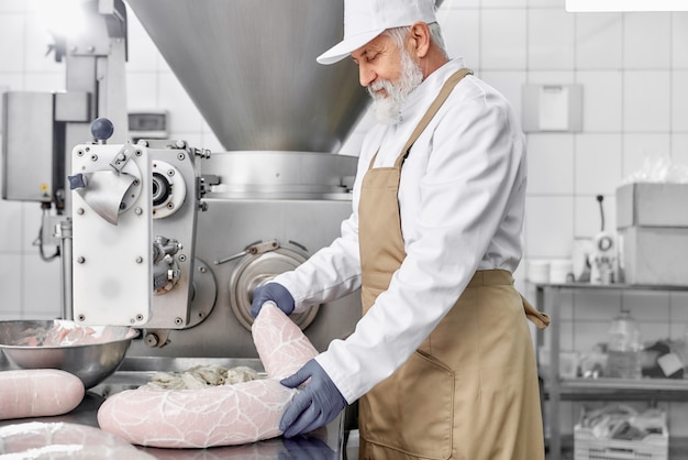 Hombre trabajando con equipos para la producción de salchichas.