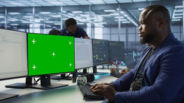 Hombre trabajando en una granja de servidores usando una computadora de pantalla verde