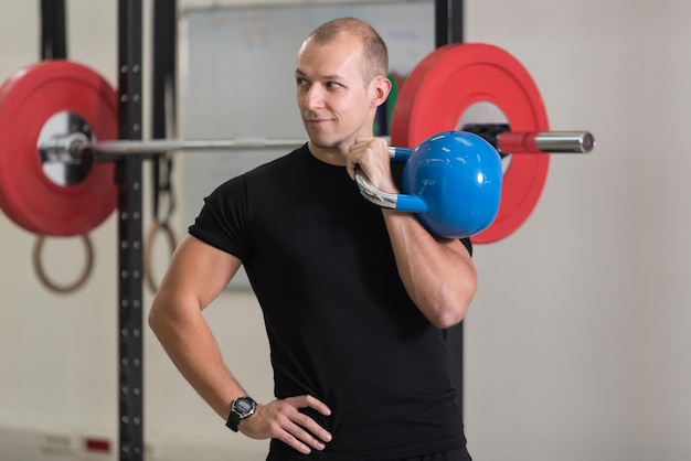 Hombre trabajando con Kettle Bell culturista haciendo ejercicio de peso pesado con pesas rusas