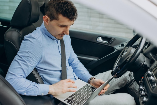 Hombre trabajando en una laptop dentro de su auto