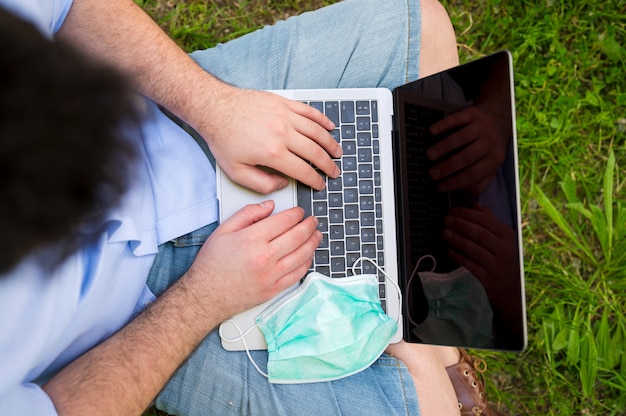 Hombre trabajando con laptop sentada en el parque