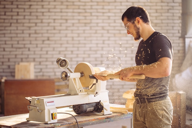 Hombre trabajando en un pequeño torno de madera, un artesano talla un pedazo de madera