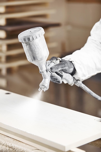 Hombre trabajando con pistola de pintura airless rociando madera