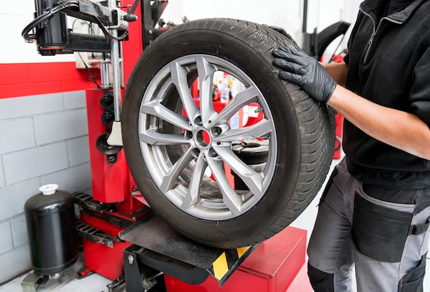 Hombre trabajando con rueda en máquina de montaje de neumáticos