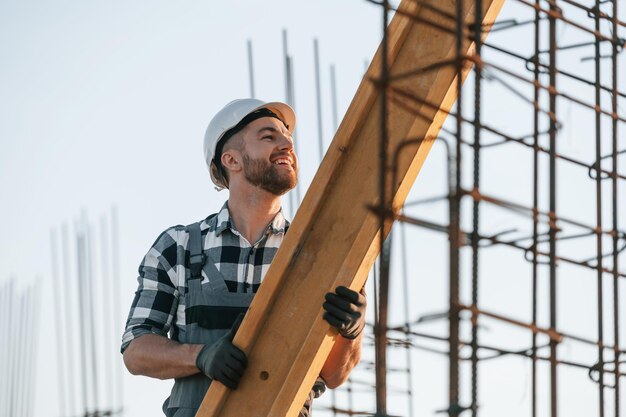 Foto el hombre está trabajando en el sitio de construcción durante el día moviendo el gran tablón de madera