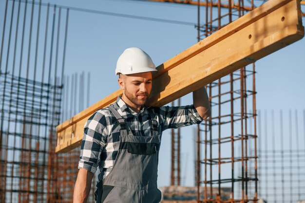 Foto el hombre está trabajando en el sitio de construcción durante el día con tablón de madera