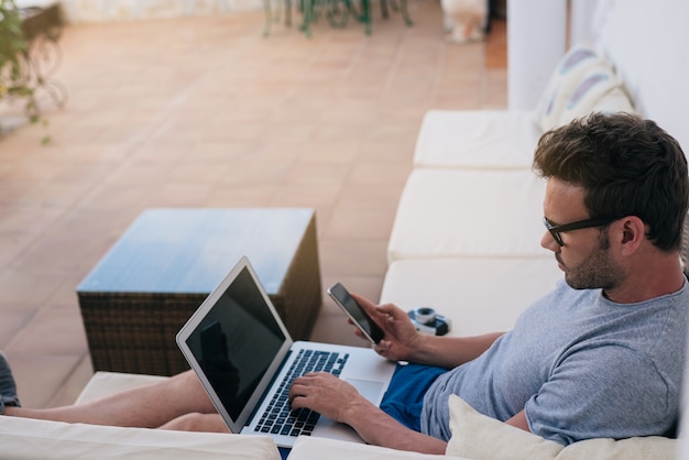 Hombre trabajando desde su casa en el patio en su computadora