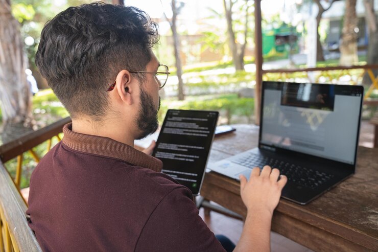 Foto hombre trabajando en su tableta y computadora portátil
