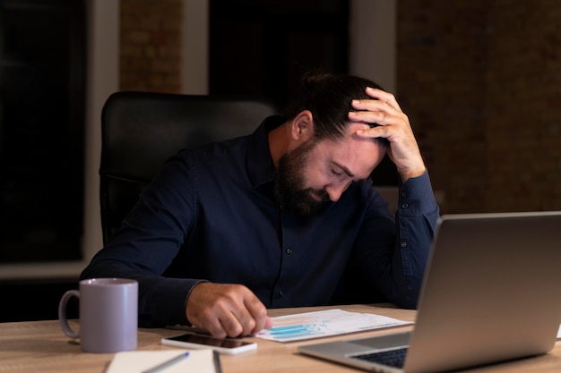 Foto hombre trabajando hasta tarde para un proyecto urgente