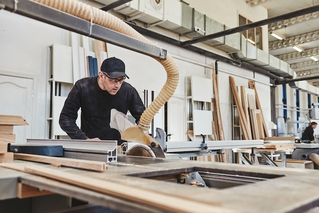 hombre en el trabajo aserrar madera sierra circular una máquina que corta tableros de partículas de madera y tableros de fibra