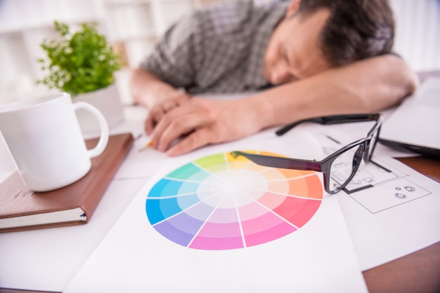 Foto hombre de trabajo cansado que duerme en el lugar de trabajo por completo de bosquejos