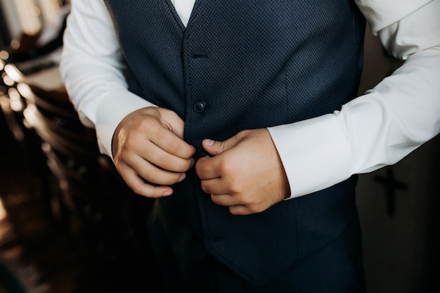 Un hombre con un traje azul se abrocha la chaqueta, de cerca. Empresario cambiarse de ropa. Corrección tonal. ESTILO DE MODA.