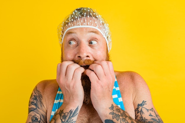 Hombre con traje de baño y gorro de pelo para mujer está listo para el verano