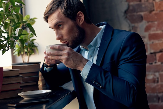 un hombre de traje bebe café cerca de la ventana de un café foto de alta calidad