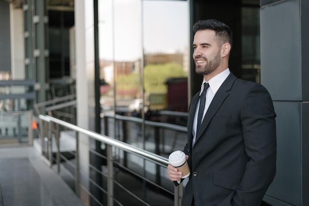 Hombre de traje bebiendo café en la calle comercial