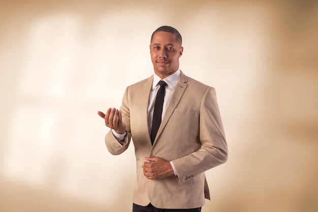 Hombre en traje beige en foto de estudio sobre un fondo con luces.