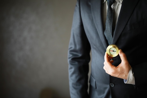 Hombre de traje con brújula dorada sobre fondo gris