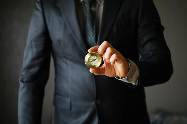 Hombre de traje con brújula dorada sobre fondo gris