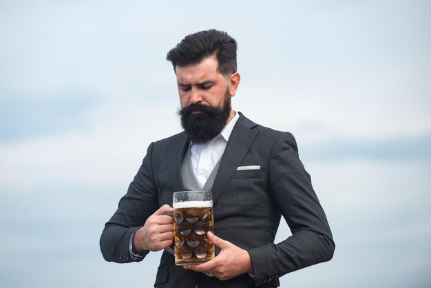 Hombre en traje clásico bebiendo cerveza retrato de hombre con vaso de cerveza levantado