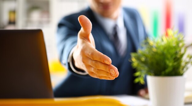 Foto hombre de traje y corbata da la mano como hola en la oficina