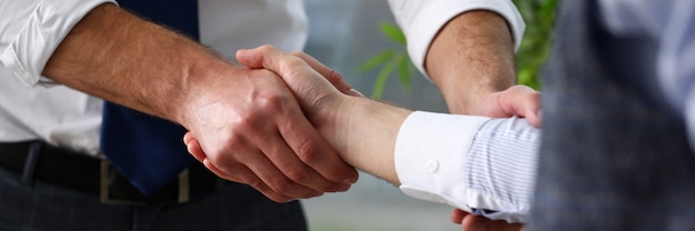 Hombre en traje y corbata dan la mano como hola en primer plano de la oficina