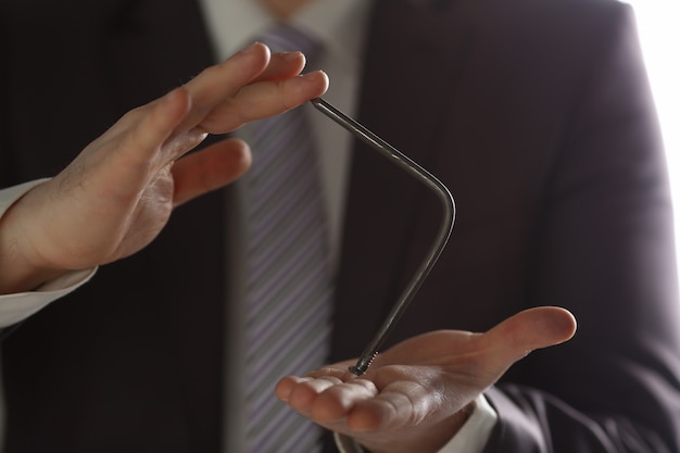 Hombre de traje y corbata doblar las uñas con brazos closeup