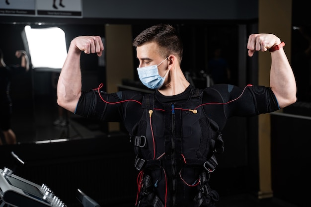 Hombre en traje de EMS y máscara médica en el gimnasio