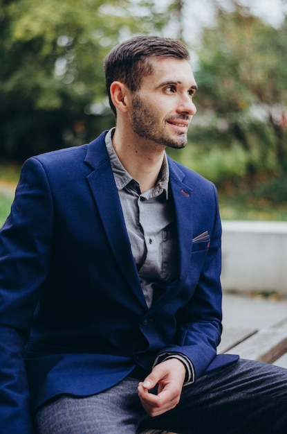 un hombre con traje está sentado en un banco y sonriendo