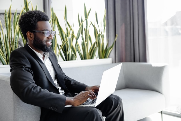 Hombre con traje de estilo oficial trabajando en línea en una computadora portátil en la oficina
