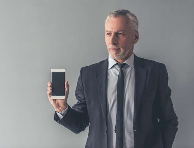 Hombre en traje formal está mostrando un teléfono inteligente