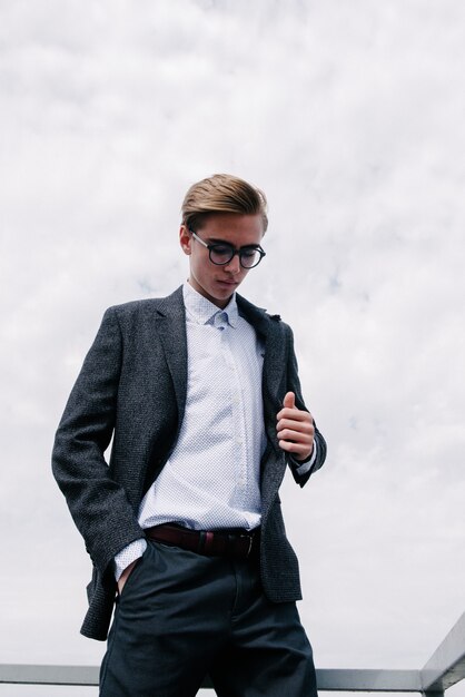 Un hombre con un traje gris y una camisa blanca posando.