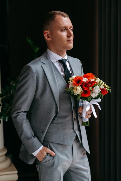 Foto un hombre en un traje gris está sosteniendo un ramo de flores