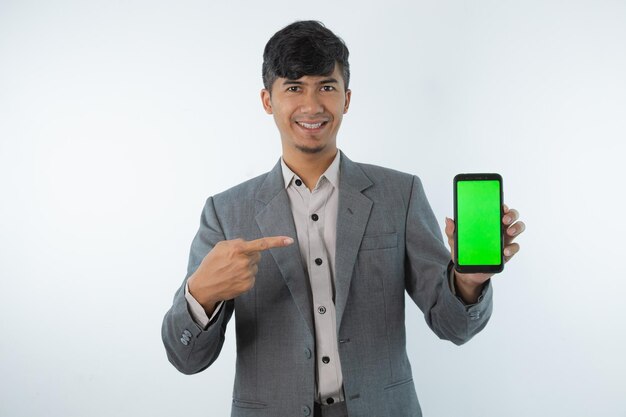 Un hombre con traje gris sostiene una pantalla verde con una pantalla verde