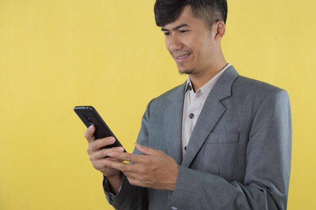 Un hombre con traje gris sostiene un teléfono en la mano.