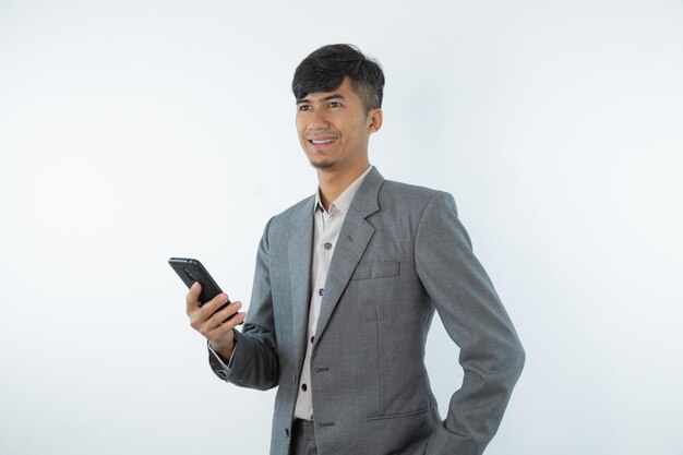 Un hombre con traje gris sostiene un teléfono y sonríe.