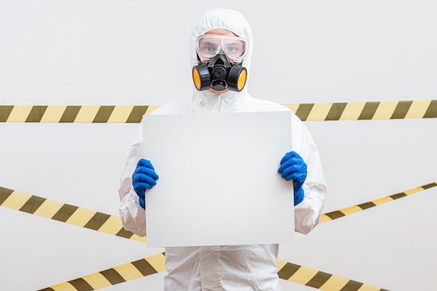 Foto hombre en traje de materiales peligrosos con un cartel en blanco