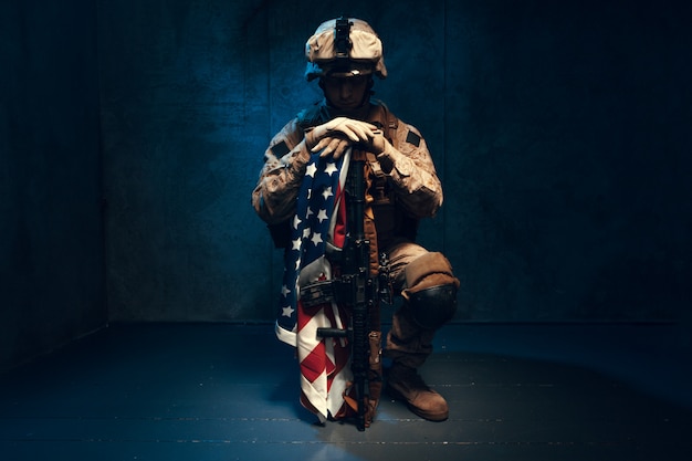 Hombre traje militar un soldado mercenario en los tiempos modernos con bandera estadounidense en estudio