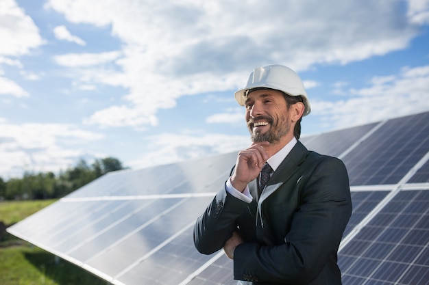 El hombre en traje de negocios felizmente smailing, paneles solares en el backstage.