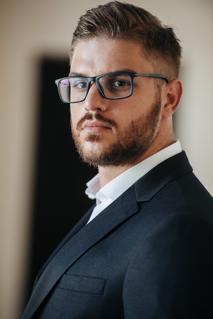 Foto un hombre con un traje negro y una camisa blanca posa en el interior para anunciar ropa de hombre. tiro para tienda de ropa masculina