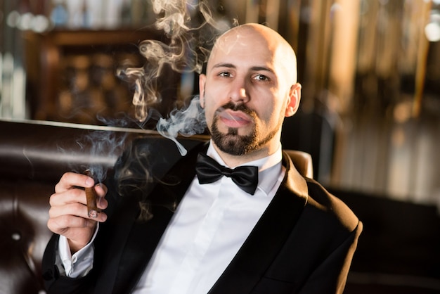 Hombre de traje negro fuma un cigarro