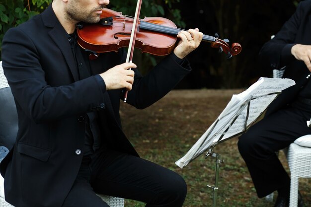 Hombre en traje negro toca el violín