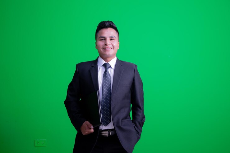un hombre en un traje de pie frente a una pantalla verde