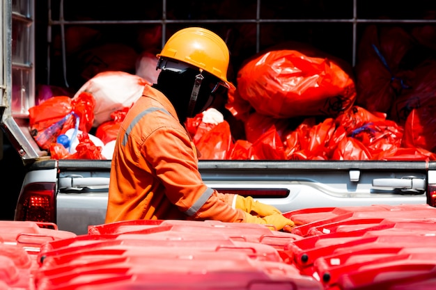 Hombre en traje de protección con contenedor de infección rojo y bolsa de residuos de infección.